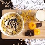 Delicious and healthy breakfast bowl with apricots, cereals, chocolate, and soy milk.