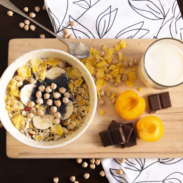 Delicious and healthy breakfast bowl with apricots, cereals, chocolate, and soy milk.