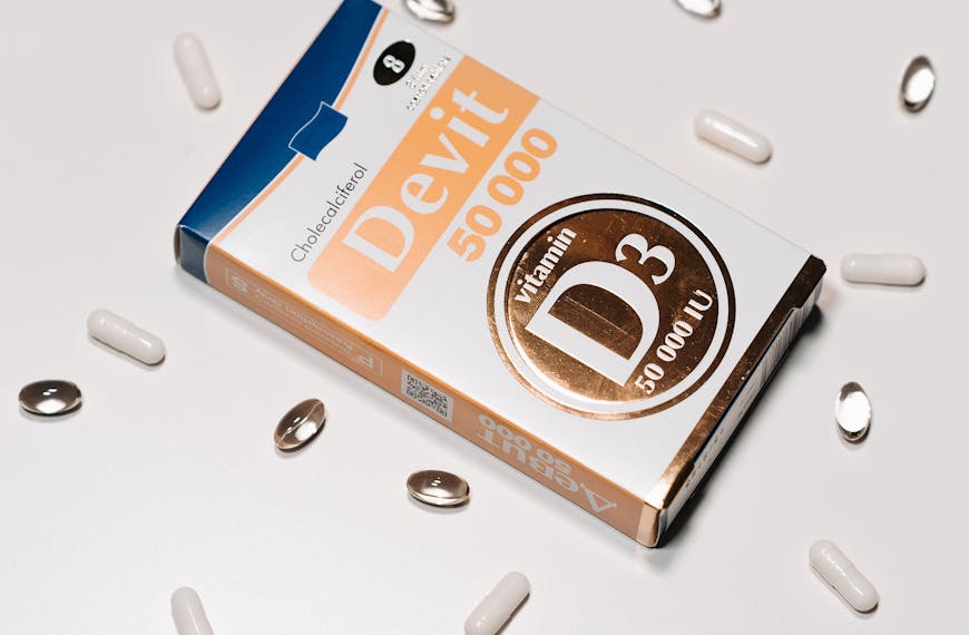 Vitamin D3 50000 IU supplement box surrounded by capsules on a white background.